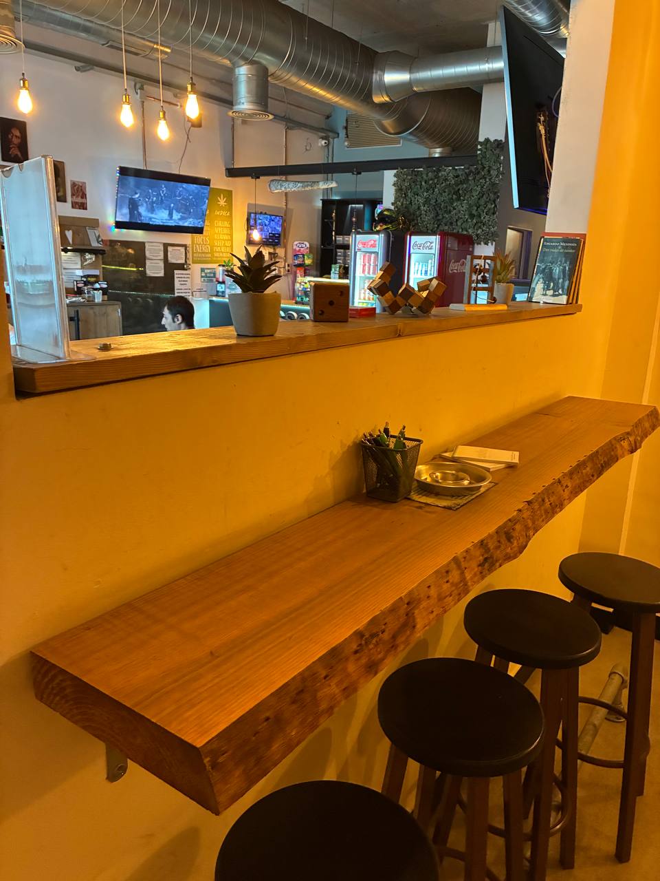 A seat at the wood, warm bulbs and a proper bar behind you.